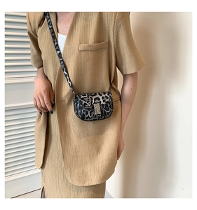 Detail of grey leopard print saddle bag featuring a stylish metal lock and leather strap
