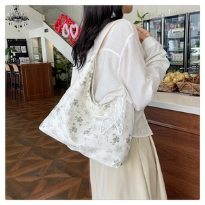 Détail d'un sac cabas en toile fleurie avec bordure en dentelle blanche et motifs verts