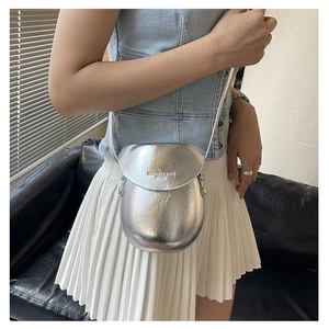 Detail of silver metallic crossbody bag with textured pleats and fashion embossed logo