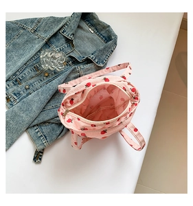 Detail view of pink corduroy tote bag featuring red strawberry prints and zipper closure