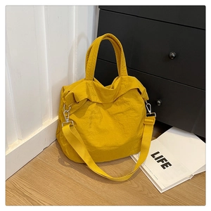 Détail du sac cabas jaune moutarde montrant le tissu texturé et les crochets en métal