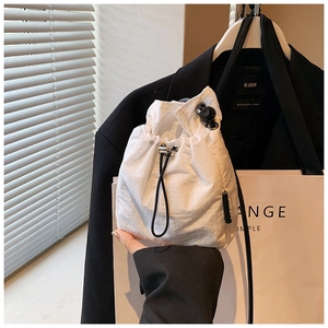 Detail of white drawstring nylon bucket bag with ripstop texture and black strap