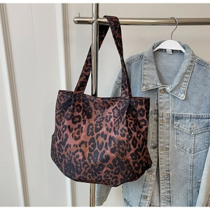 Detail of large capacity leopard print tote bag hung with denim jacket for daily outfit