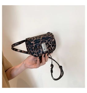 Close-up of leopard print mini saddle bag featuring silver metal buckle and adjustable strap