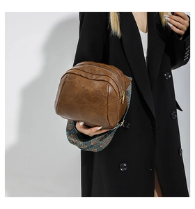 Nahaufnahme der braunen PU-Leder-Tasche mit buntem gewebtem Schultergurt im Ethno-Stil