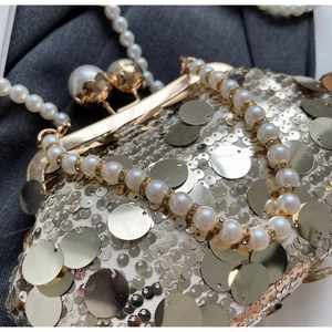 Macro shot of sequins and pearl handle on a luxury evening clutch bag with clasp detail