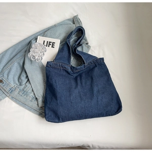 Close-up of deep blue denim tote bag featuring orange contrast stitching and soft texture