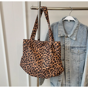 Detail of canvas tote bag with brown leopard print hanging next to a denim jacket