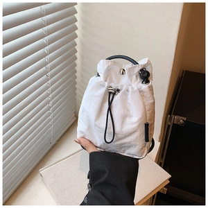 Detail of white ripstop nylon bucket bag with black drawstring and ring handle