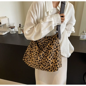 Detail of a large leopard print canvas tote bag with brown leather shoulder straps
