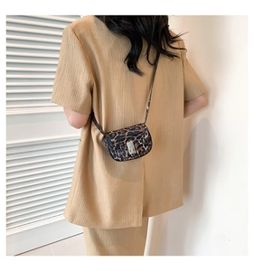 Detailed view of leopard print mini crossbody bag with silver buckle worn by a model