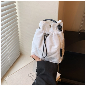 Detail of white quilted nylon bucket bag with black circular handle and drawstring closure