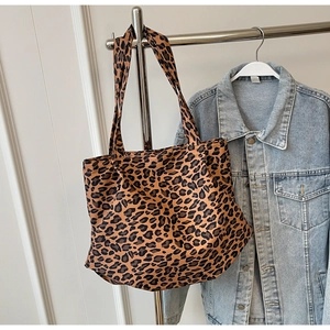 Macro detail of high-capacity leopard print tote bag hanging with denim jacket