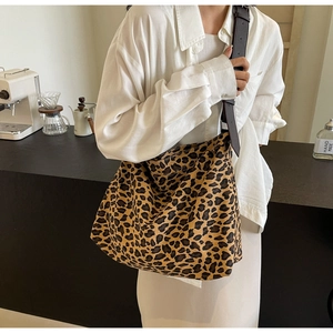 Detail of adjustable leather strap and leopard print canvas tote bag on female model