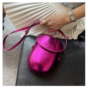 Macro shot of fuchsia metallic saddle bag featuring embossed fashion leather logo detail
