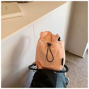Detail of light pink mini nylon bucket bag with black drawstring and toggle closure