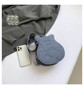 Detail shot of guitar-shaped denim crossbody bag featuring metal rivets and adjustable strap
