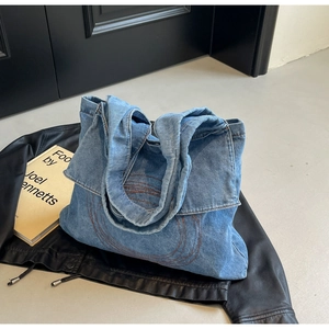Detailed view of blue denim tote bag featuring concentric circular stitching and textured fabric