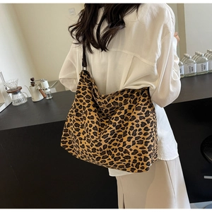 Lifestyle view of large leopard print canvas tote bag carried by a model in a cafe
