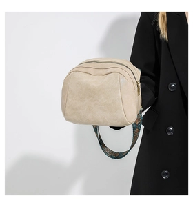 Detailaufnahme der beigen Muschel-Tasche mit einem breiten Schultergurt im Ethno-Stil