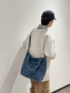 Grande borsa tote in denim blu con tracolla regolabile vista da una prospettiva laterale