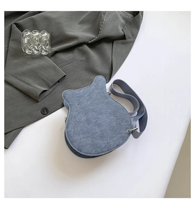 Detail view of light blue guitar-shaped crossbody bag with soft suede texture and wide strap