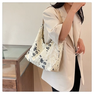 Détail d'un sac cabas en toile fleurie avec bordure en dentelle blanche et motifs de feuilles
