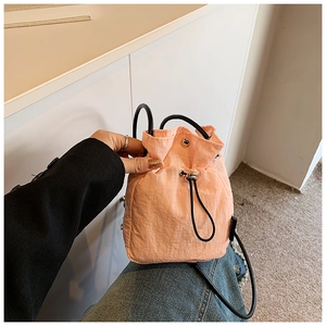 Macro detail of peach nylon drawstring bucket bag with textured square grid pattern