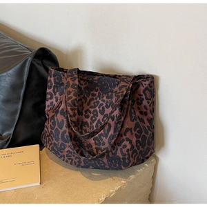 Macro view of leopard print tote bag on stone base with decorative book and accessories