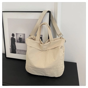 Détail d'un sac cabas beige texturé avec poignées et bandoulière réglable