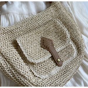 Detailaufnahme der Stroh-Schultertasche mit braunem Lederriemen und kleiner Fronttasche