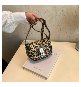 Close-up of leopard print saddle bag with silver metal twist lock on a white book