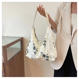Détail du sac cabas floral avec un élégant nœud en dentelle et une bandoulière en cuir
