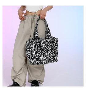 Detailed view of large leopard print canvas tote bag carried by a fashion model