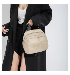 Beigefarbene Muscheltasche mit ethnischem Trageriemen kombiniert mit schwarzem Blazer