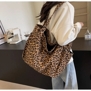 Dettaglio della borsa tote grande in tela con stampa leopardata indossata in un caffè