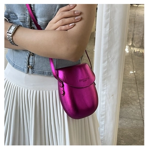 Detail view of metallic magenta mini crossbody bag on model with embossed logo
