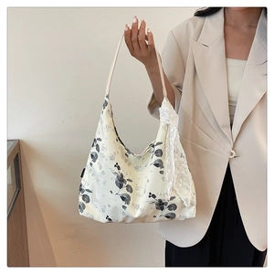 Détail du sac cabas floral en toile avec écharpe en dentelle blanche et motif feuilles
