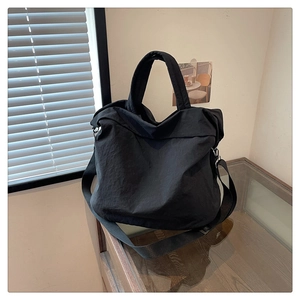 Détail d'un grand sac cabas noir minimaliste en tissu plissé avec bandoulière large