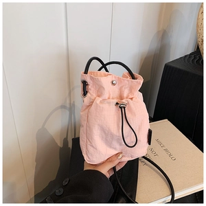 Detail view of pink nylon drawstring mini bag featuring a stylish quilted texture and metal clasp