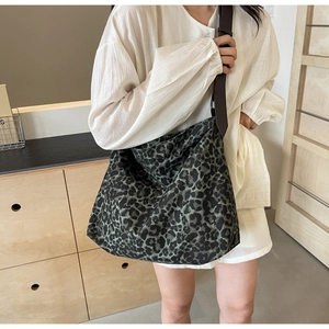 Detail of dark leopard print canvas tote bag with brown leather strap on model