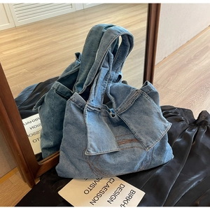 Close-up of blue denim tote bag with decorative bow fold and brown wavy stitching