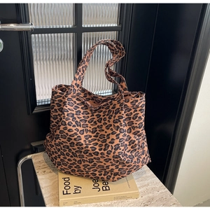 Detail of large leopard print tote bag with thick straps on a minimalist marble stand