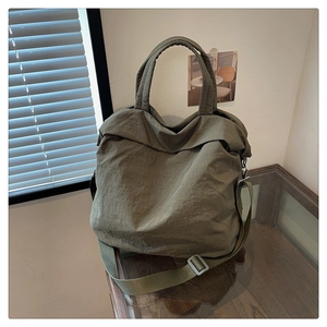 Détail du sac fourre-tout en nylon vert olive avec bandoulière et design supérieur plié