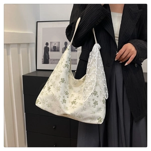 Détail du sac cabas floral en toile avec motifs verts et ruban de dentelle blanche