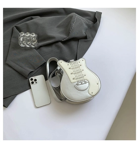 Detailed macro shot of creative guitar-shaped silver leather crossbody bag with metal rivets