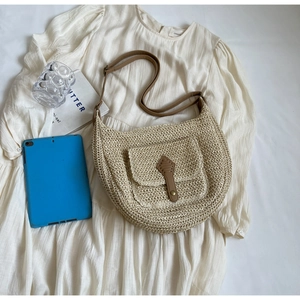 Detailansicht der gewebten Strohschultertasche mit brauner Lederschnalle auf weißem Kleid
