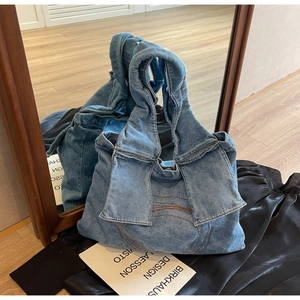 Detail of denim handbag with large bow handle and brown wavy stitching accents