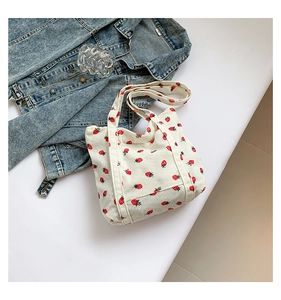 Detailed close-up of white corduroy tote bag with vibrant red strawberry print and denim