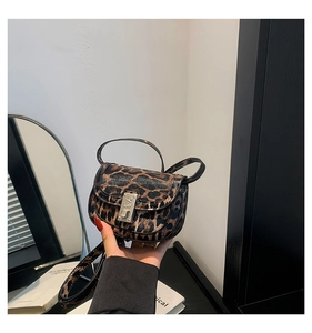 Close-up of leopard print saddle bag with silver metal buckle and adjustable shoulder strap